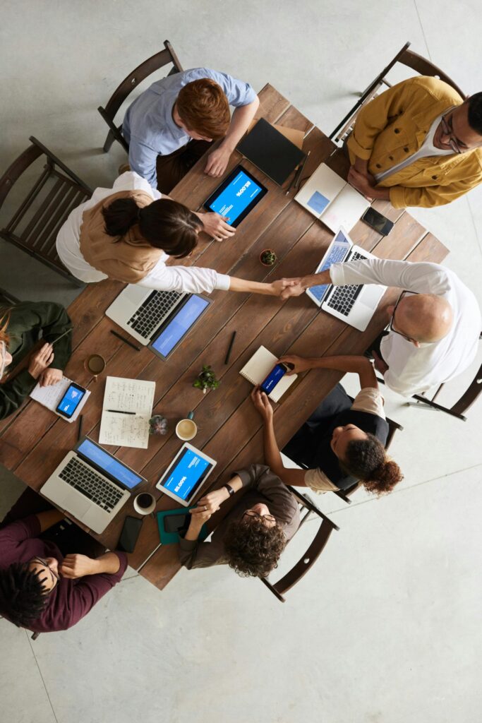 Top view of a diverse team collaborating in an office setting with laptops and tablets, promoting cooperation.