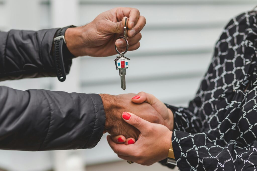 Close-up of a realtor handing over a house key to a new homeowner, symbolizing ownership and investment.